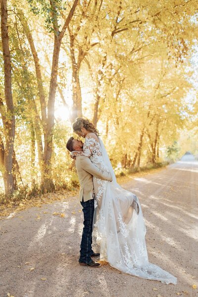 bride jumping up on groom with her feet high looking at each other. Captured by Michelle Colorado wedding photographer