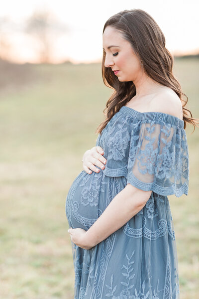 Pregnant mother holding her pregnant belly at sunset outside by Washington DC Family PhotographerWashington DC Family Photographer