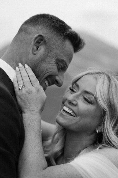 Black and white photo of a couple laughing with each other during a candid moment.