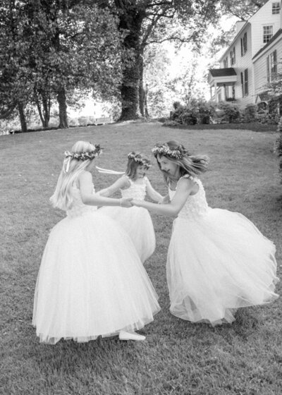Joyful black and white moment of flower girls playing on grass – Luxury Wedding Photography Seattle