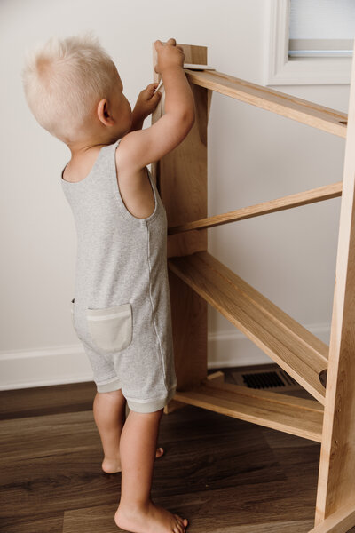 Flat lay of baby clothing and accessories styled on a neutral background.