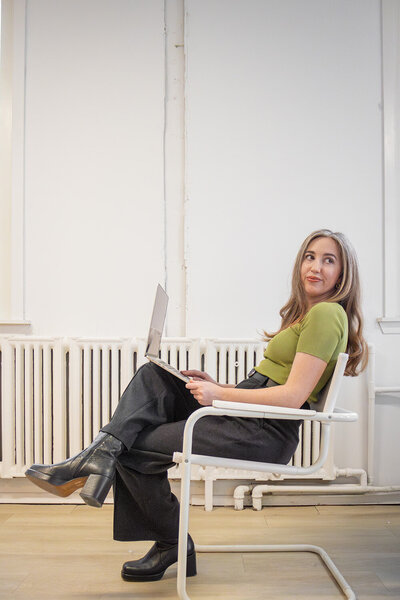 Content repurposing strategist seated on a chair working on a laptop in a minimalist room.