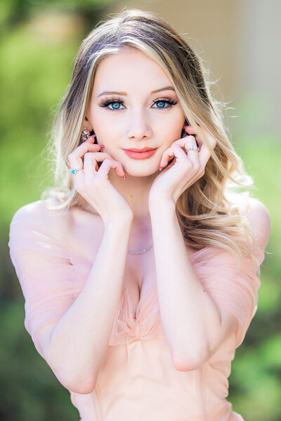 beautiful blonde girl with blue eyes with hands on face like an editorial model