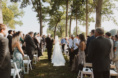 Photo from behind of bride walking down the outdoor aisle