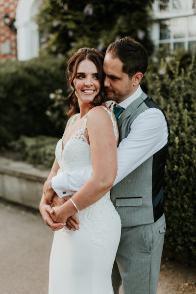 Bride and groom posing for portrait with white walls