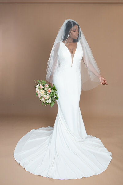 Bride wearing a two layered fingertip length veil and holding a white and blush bouquet