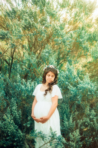 Woman in white maternity dress posing in flowers in the hills of Malibu in Southern California