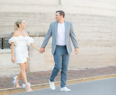 Couple holding hands and crossing the street by the Lightner Museum during their engagement session