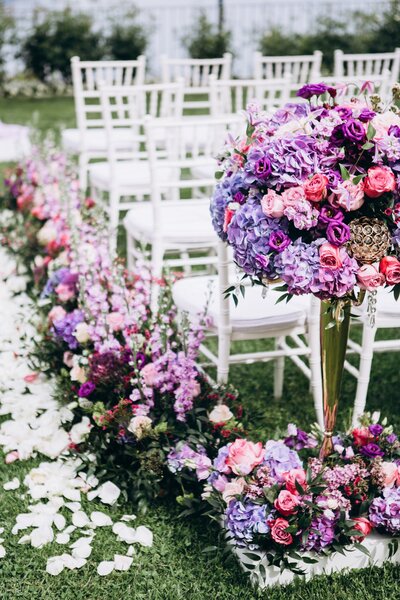 Purple wedding florals lining the aisle