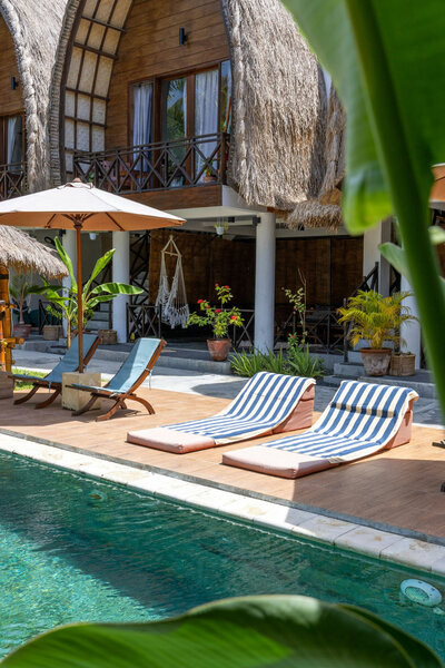 Swimming pool with chairs and umbrellas in front of a house