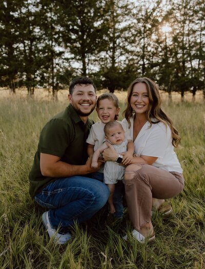 Outdoor family photo session in Nebraska, with a joyful family posing in a scenic field during golden hour, capturing the warmth and connection of the moment.