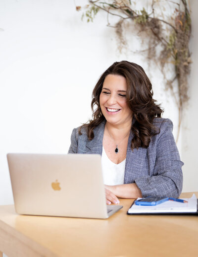 Dr. Chris Limone at a desk with a laptop, smiling warmly while working online
