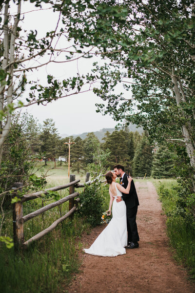 Bride and groom kissing in a meadow at Wild Basin Lodge