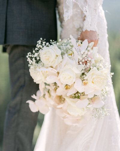 This stunning photograph captures a bride holding her bouquet while her husband lovingly holds her tight in Banff National Park. The breathtaking landscape adds to the romance of the moment, reflecting the beauty of their connection and the natural surroundings.