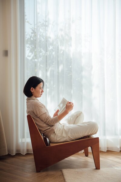 A woman sitting on a chair reading through her CTNC material.