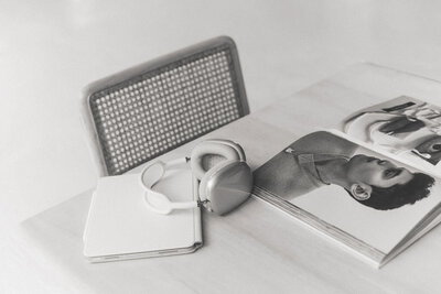 Headphones rest on an open book next to a laptop