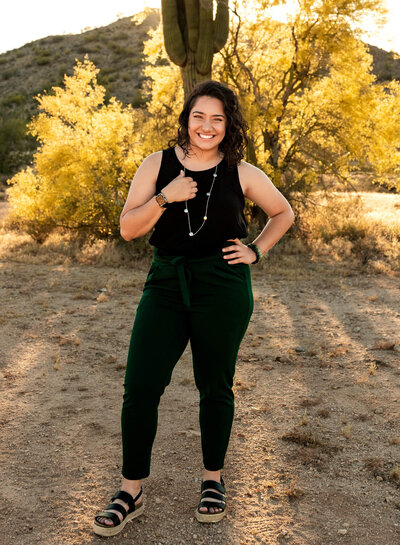 Cactus & Pine Photography owner standing and smiling in the desert at sunset