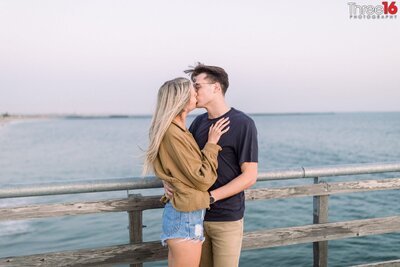 Engaged couple share a kiss on the Seal Beach Pier