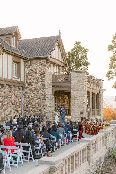 Bride and groom sharing a kiss in front of Highlands Ranch Mansion, a classic Colorado wedding venue with white columns and historic charm.