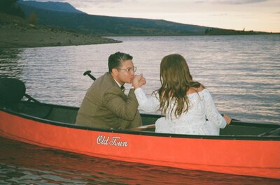 Groom kissing bride's hand during a canoe ride on Lake Dillon after their elopement 