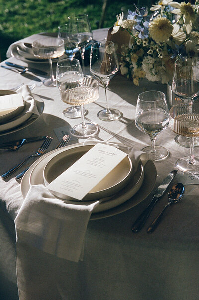 A round table set for a wedding reception with simple, elegant decor and soft natural tones.