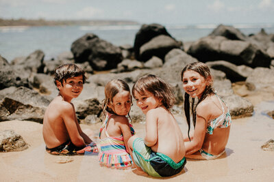 kids sitting in a tide pool at anahola beach