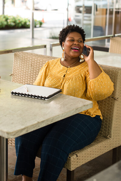 Woman sitting at an outdoor table talking on phone and smiling