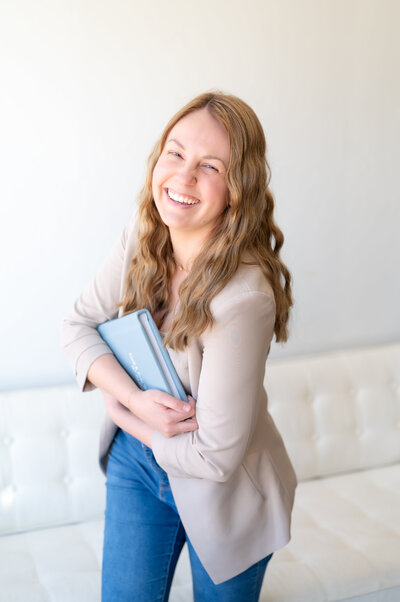 Photographer smiling holding a wedding photo album in her hands