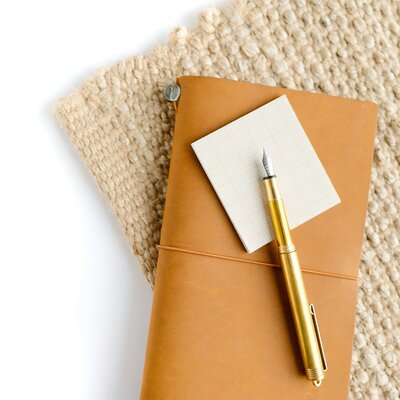 Pen, paper, and notebook stacked on top of a textured background