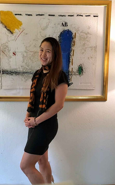 Asian-American woman is standing in front of a modern art piece.