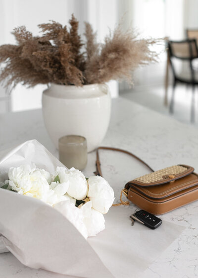 Flowers and bag on top of white marble table