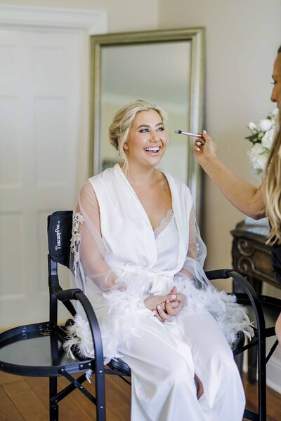Bride sitting in chair getting makeup completed