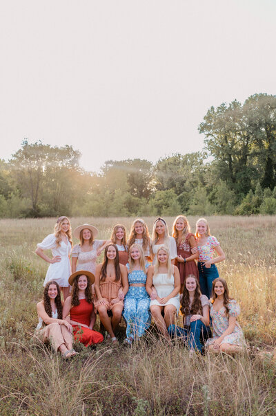 Rachel B Photography's Senior Rep Team of 14 girls pose together in an open field all smiling at the camera.