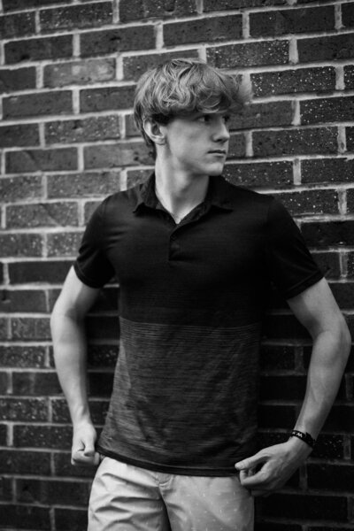 A striking senior portrait captured outdoors against a brick wall in Urbana, IL. Light By Zoey Photography provides senior portrait sessions for high school seniors in Champaign-Urbana.