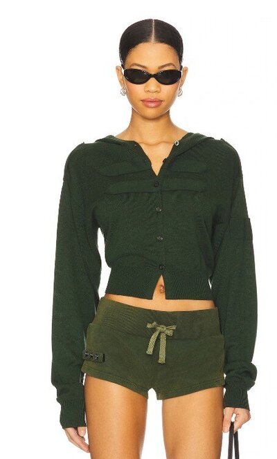 Model wearing a fall matching set with a dark green button-up cropped hoodie cardigan and olive green drawstring shorts, styled with black sunglasses.