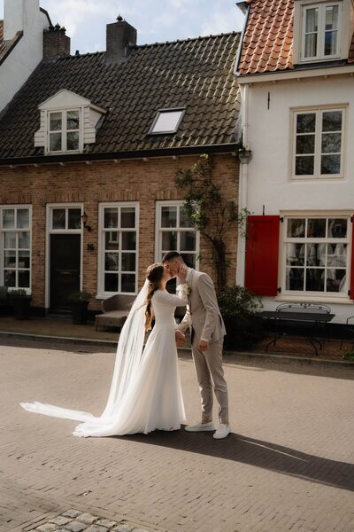 Getrouwd koppel wandelt op straat voor een huis, vastgelegd door trouwfotograaf Julia de Groot