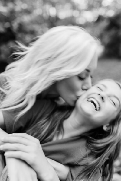 Black and white image of teenager girl laughing with mom looking at her sweetly and dad laughing to her other side.