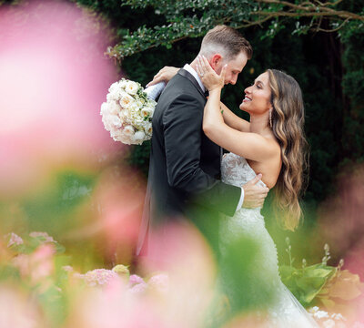 Bride and groom hugging and kissing surrounded by spring flowers | English Manor Wedding | Ocean Township, New Jersey