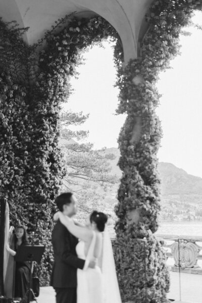 Romantic couple sharing a moment under ivy-covered arches in a garden setting.