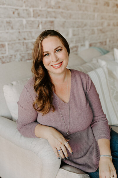 Smiling and Sitting on a Beige Couch - GariAnn Hedquist – Lead Planner & Coordinator at Tin Sparrow Events