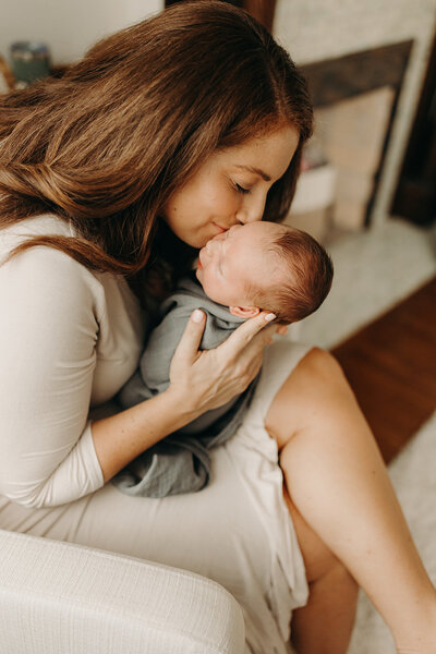 Mother kissing infant son during St. Louis newborn photos