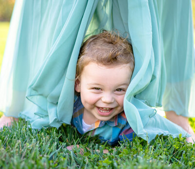 Little boy, Lincoln Shaw, giggles as his mom ruffles her dress beside him at the Columbus Park of Roses.