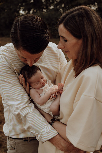 Mama en papa omhelzen pasgeboren baby tijdens newborn fotoshoot