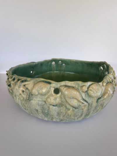 Jill stands beside her teal vase with relief detailing inside of The Studios of Key West