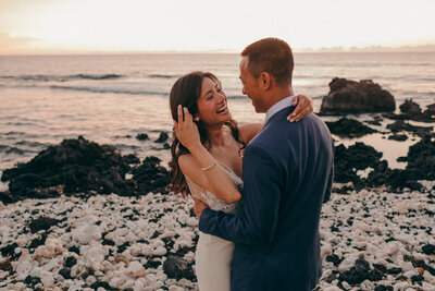a close up photo of a bride and groom laughing on the breach