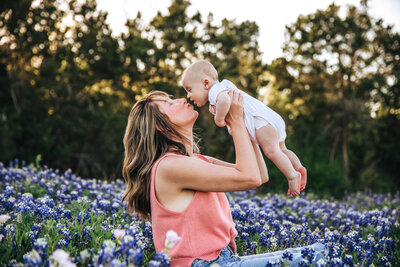 Ali holding her newborn son in a field of flowers