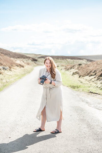 Sophie Siddons laughing holding a camera in the Welsh countryside