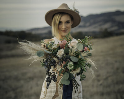 bride wearing a hat holding her bouquet