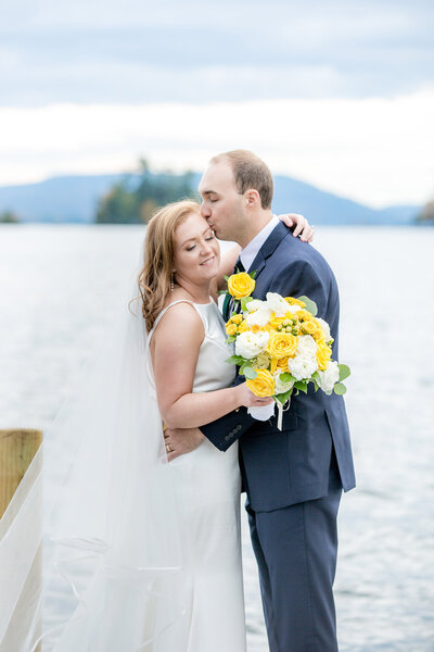 Bride and groom standing next to Lake George, NY