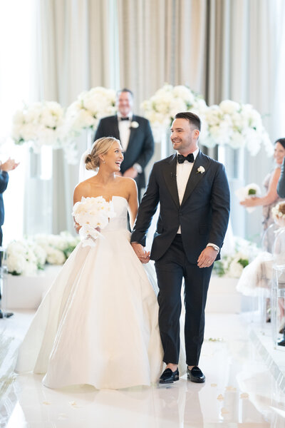 Bride and groom walk back down the aisle smiling after getting married